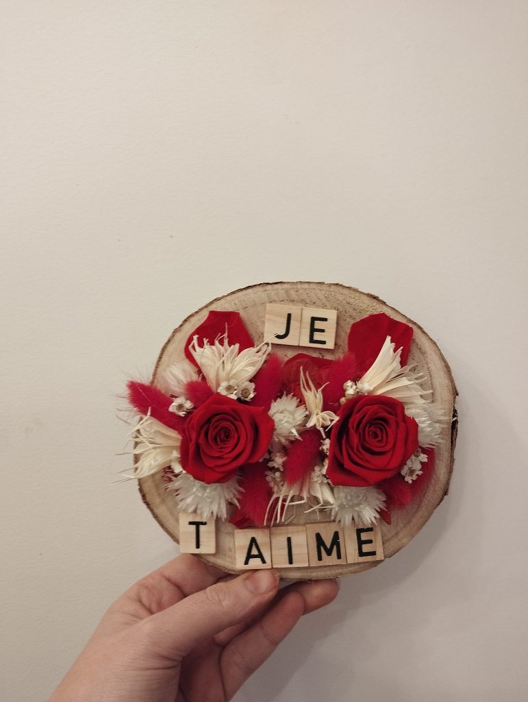 Rondin fleuri composé de roses rouges stabilisées et de fleurs séchées accompagnée du message je t'aime en lettres en bois je t'aime